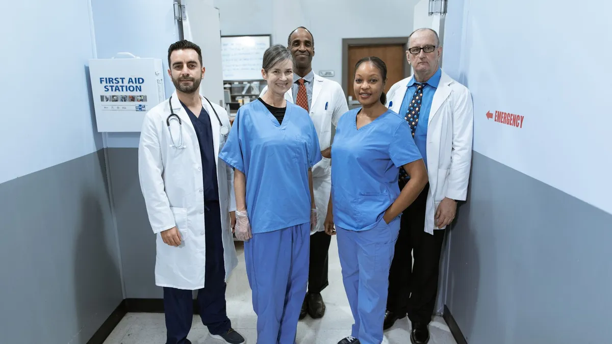 Group of diverse healthcare professionals smiling in a hospital hallway.