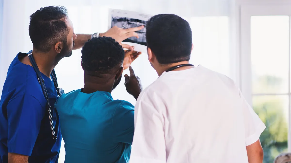 Doctors collaboratively analyzing an X-ray in a clinical setting, showcasing teamwork and medical expertise.