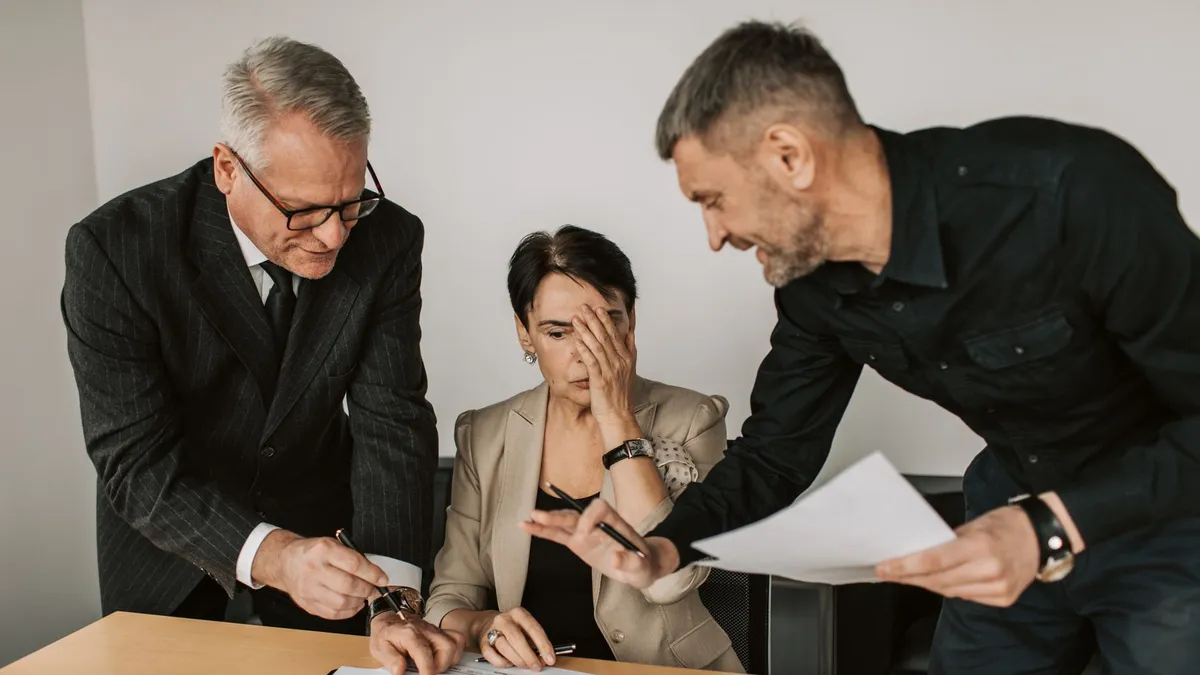 Business team in a tense meeting analyzing charts and reports at an office desk.