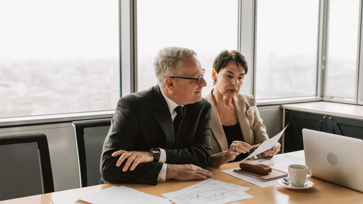 Two business professionals analyzing financial papers in a modern office setting.