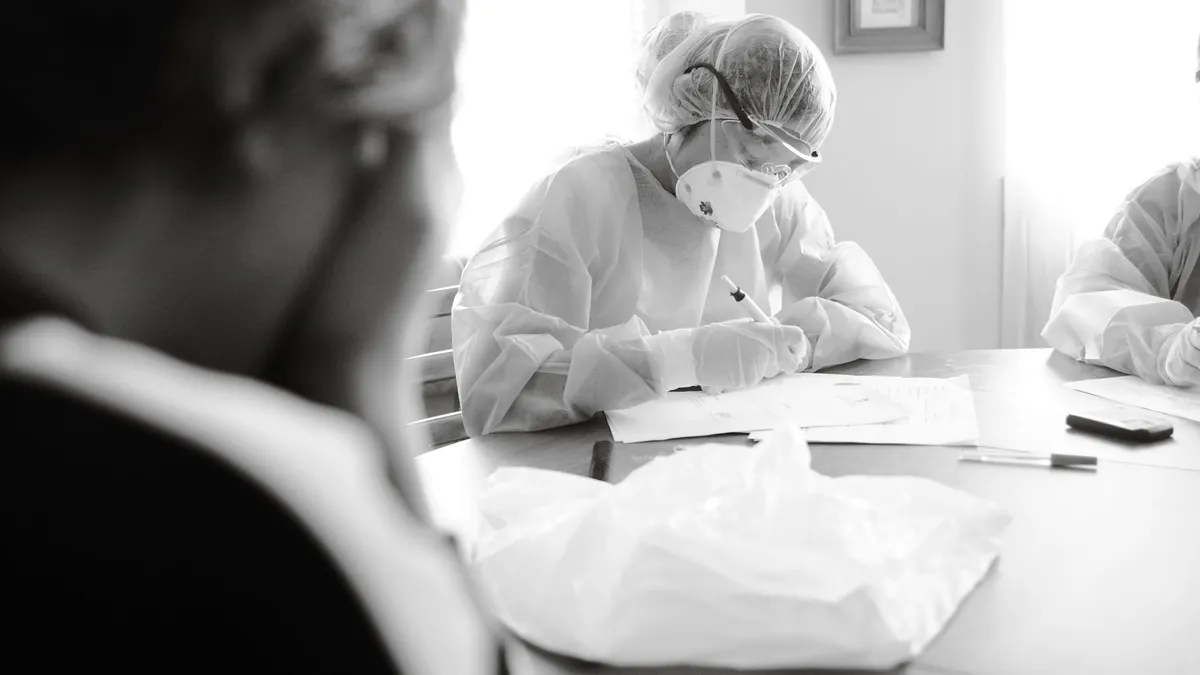 Healthcare professionals in protective gear working diligently at a table indoors.