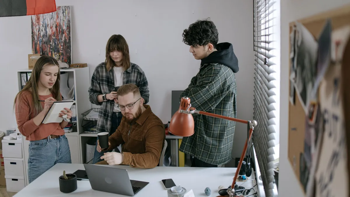 Group of young professionals having a team meeting around a laptop in a modern startup office.