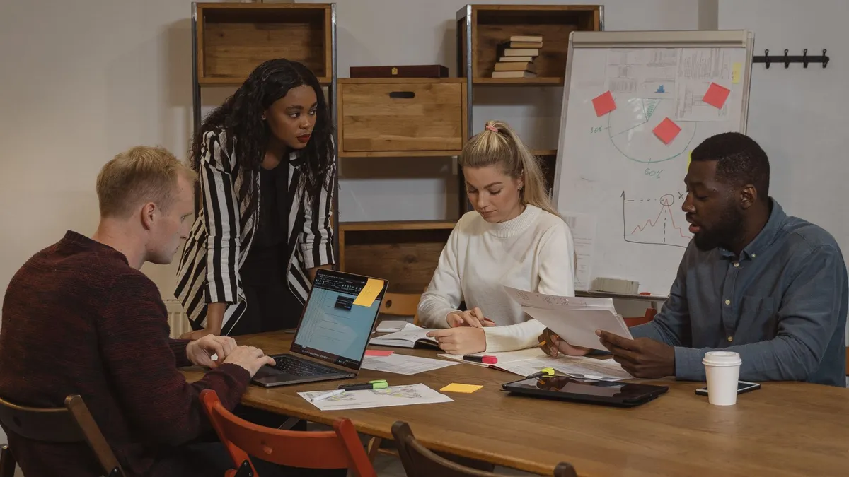 A multicultural team collaborating in a modern office setting with laptops and graphs.