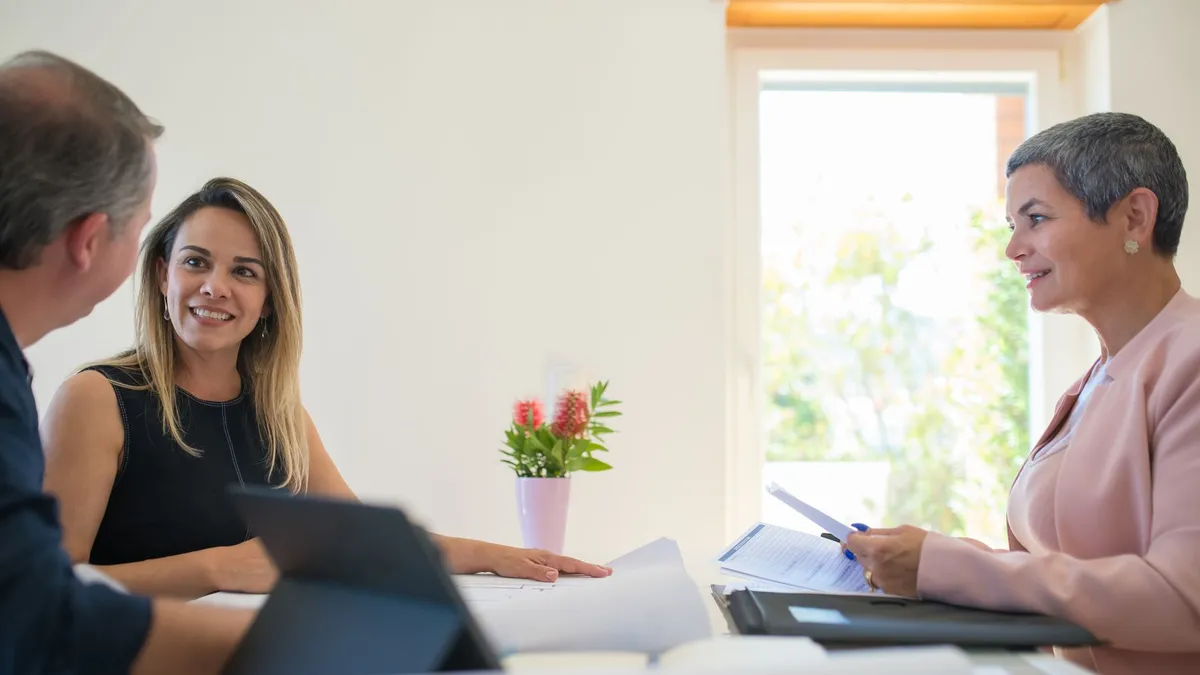 Three colleagues engaging in a friendly business meeting in a bright office space.