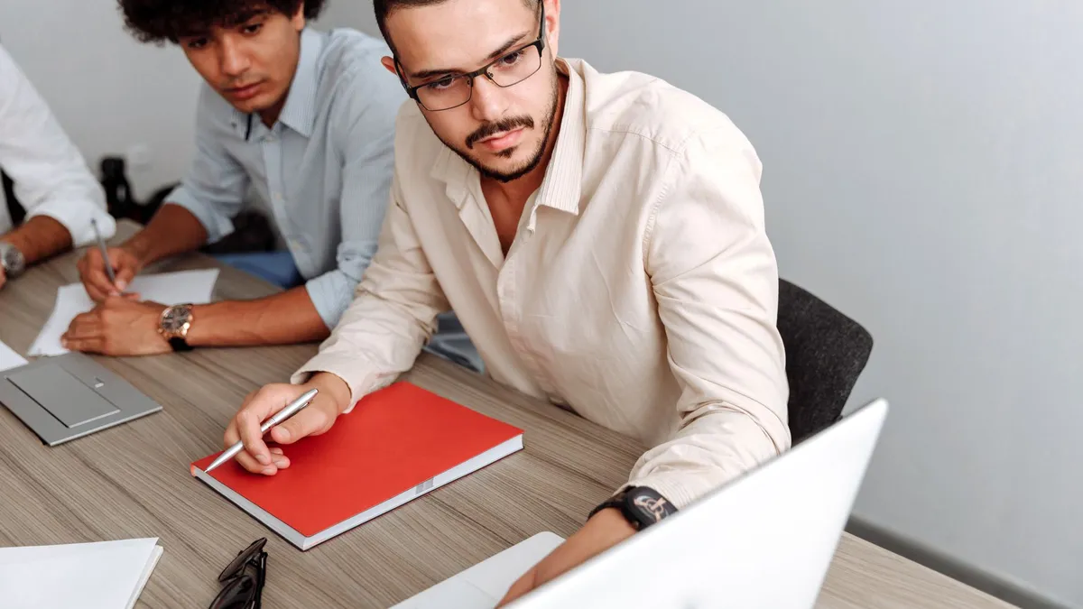 Two professionals brainstorming at an office, focused on teamwork and planning with a laptop.