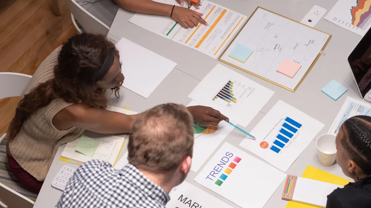 Team of professionals collaborating on a business project, analyzing charts and graphs in an office setting.