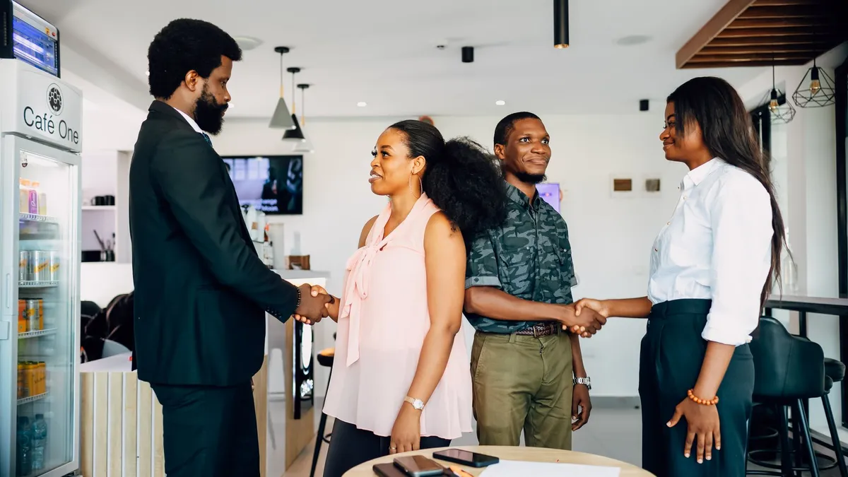 Business meeting with handshake in a modern Lagos cafe, showcasing collaboration and teamwork.