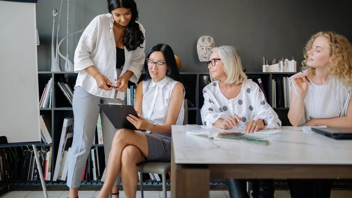 Four women collaborating in a contemporary office setting, focusing on teamwork and diversity.