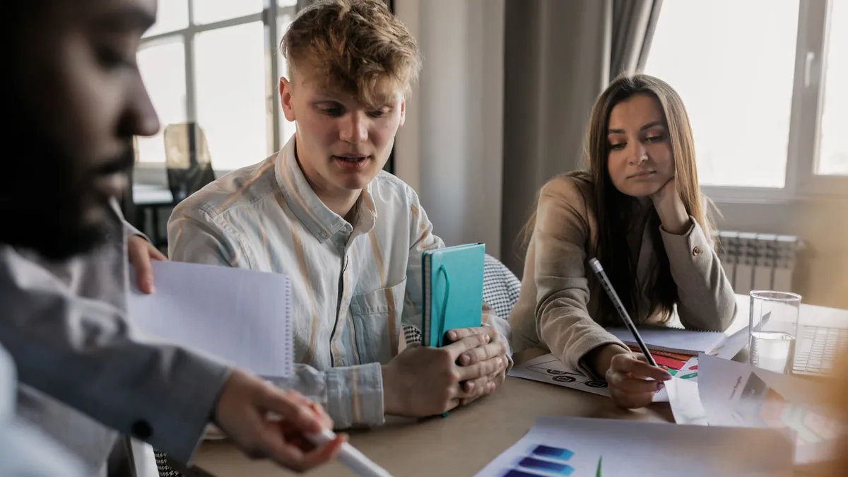 A diverse team of young professionals engaged in a business meeting analyzing graphs and data.