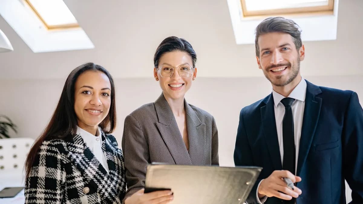 A diverse group of professionals smiling confidently in a modern office environment.
