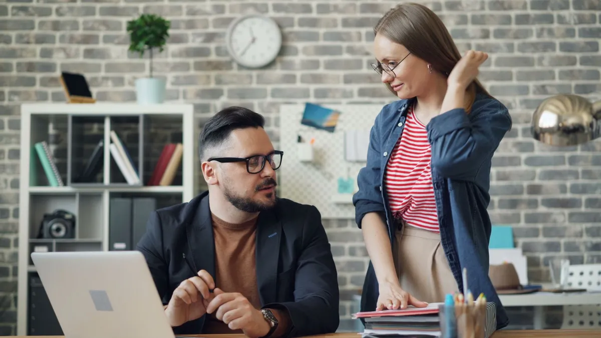 Business professionals discussing work at a desk in a contemporary office setting.