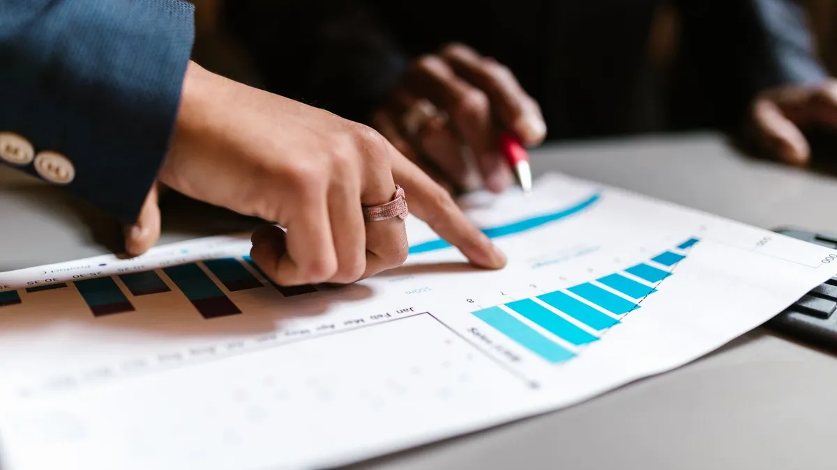 Close-up of hands analyzing financial charts during a business meeting.