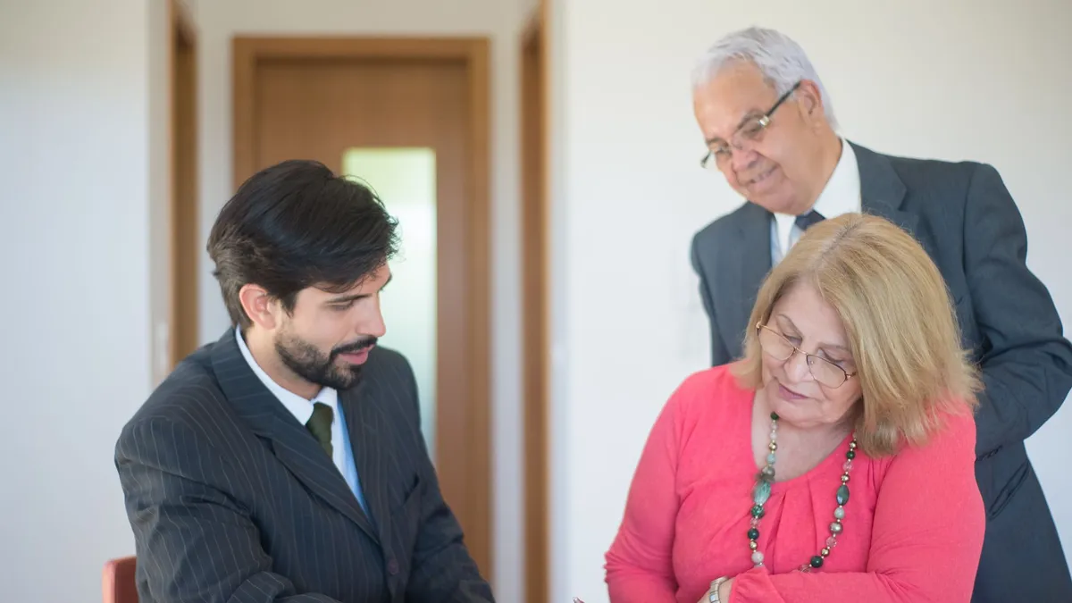 Senior couple signing real estate documents with an agent in a modern office setting.