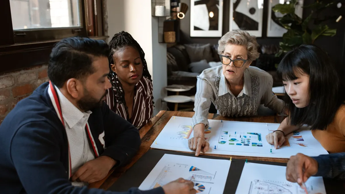 A diverse group of professionals brainstorming over charts in a stylish office setting.