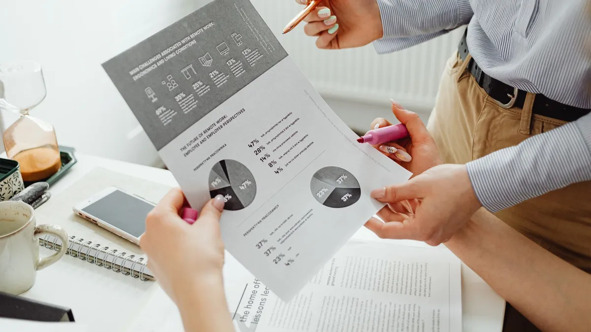 A close-up view of two colleagues analyzing business graphs and charts together.
