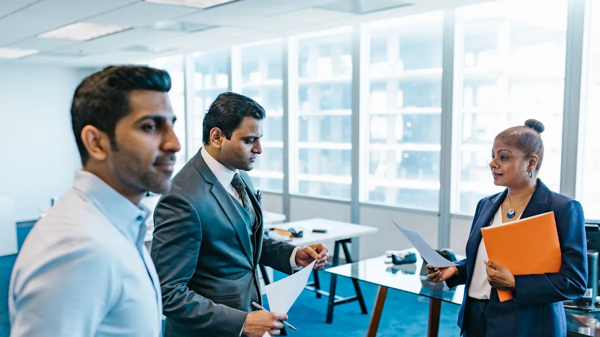 Business professionals discussing documents in a modern office environment.