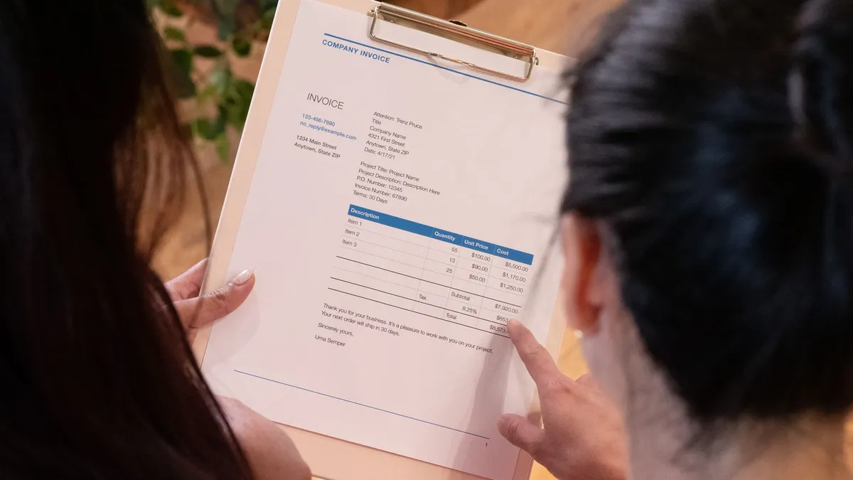 Two individuals reviewing an invoice together in a modern office setting.