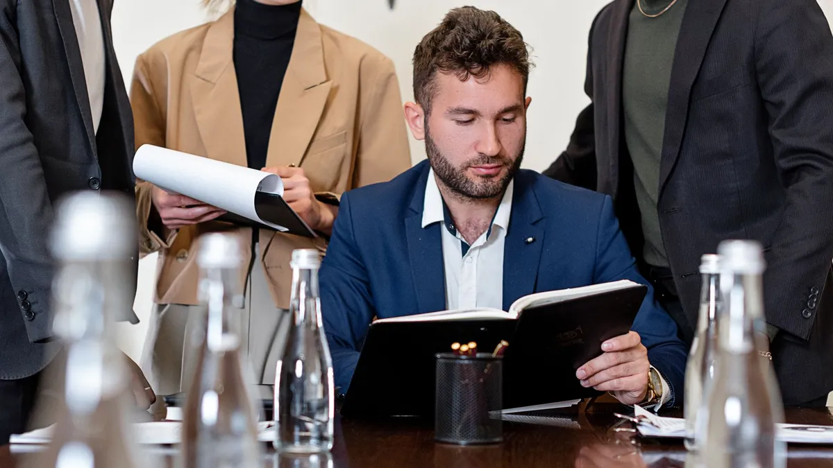 A professional team in business attire reviewing documents during a meeting.