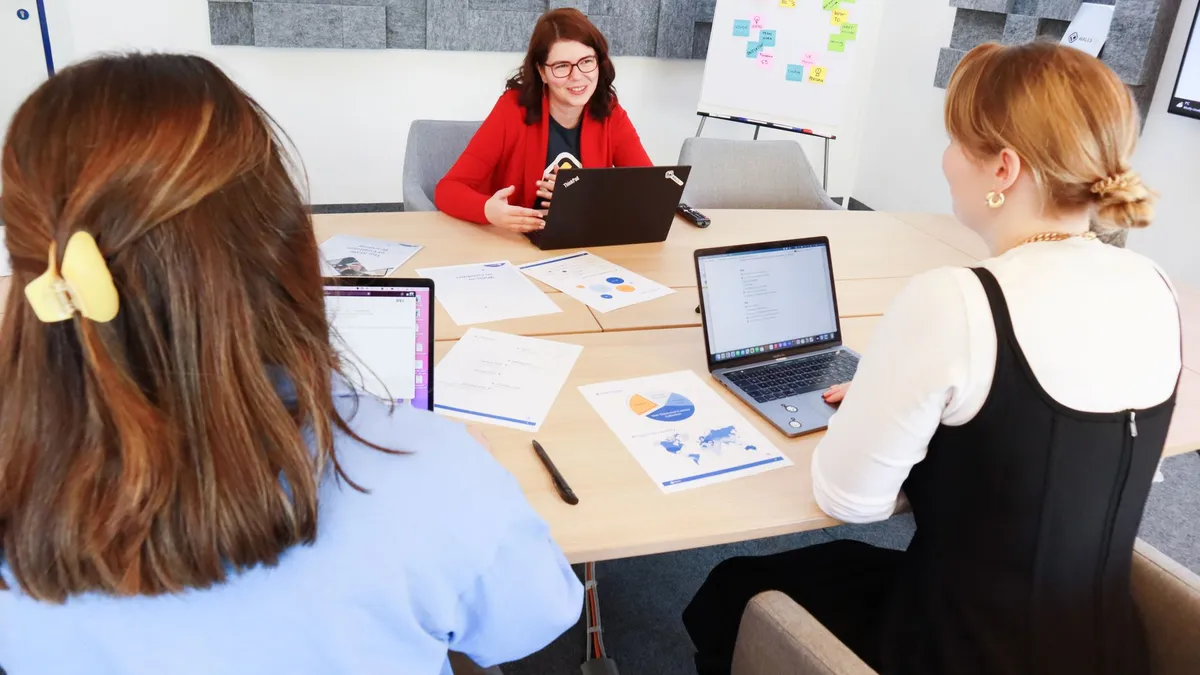 Women discussing business strategy in an office with laptops and charts.