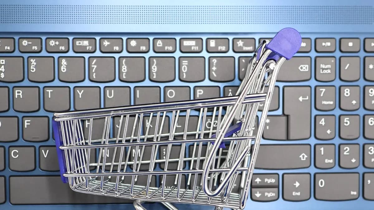 A miniature shopping cart placed on a laptop keyboard symbolizing online shopping and e-commerce.