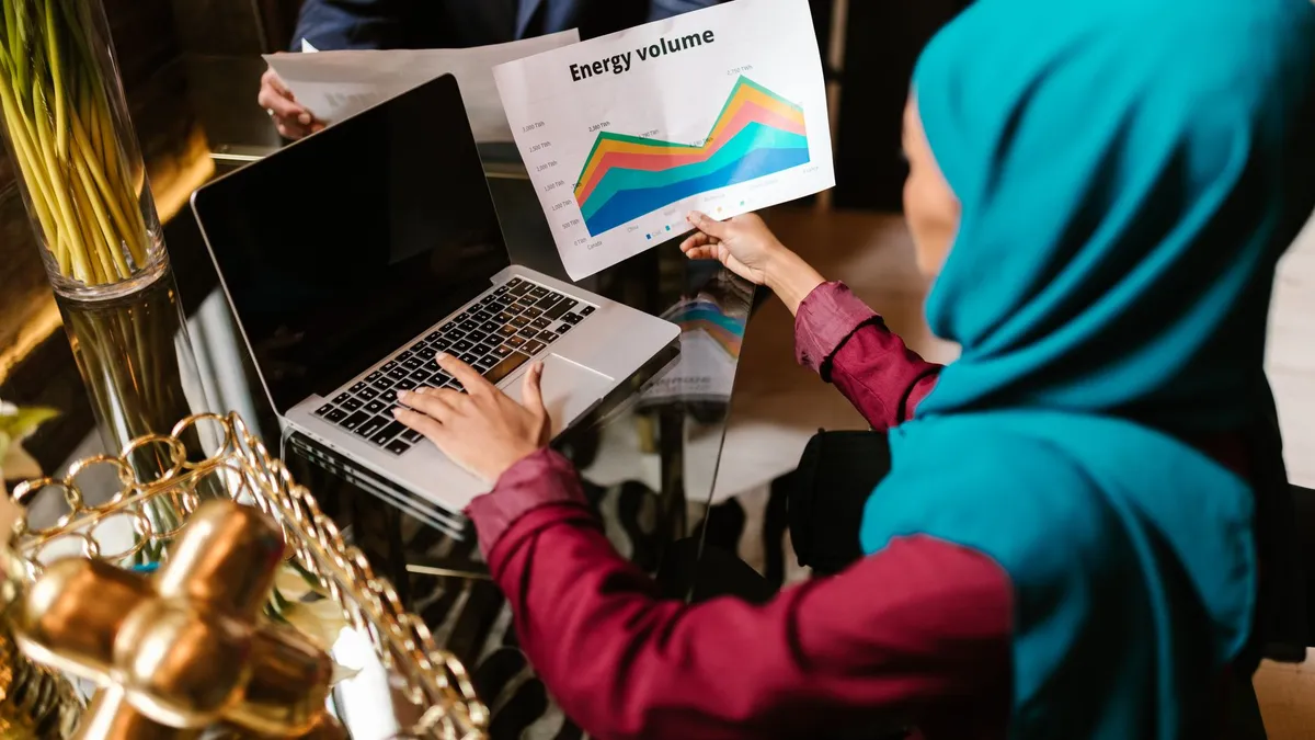 Muslim woman analyzing energy volume data during a business meeting.