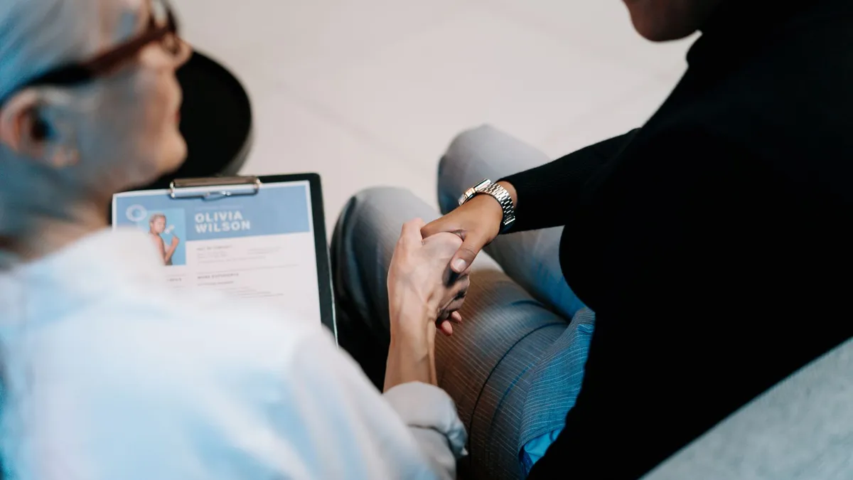 Two professional women having a handshake in an office setting, focusing on recruitment and connection.