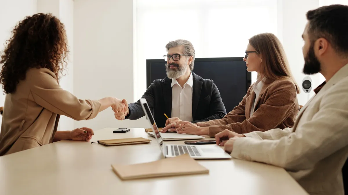 Colleagues in an office celebrating a successful negotiation with a handshake.