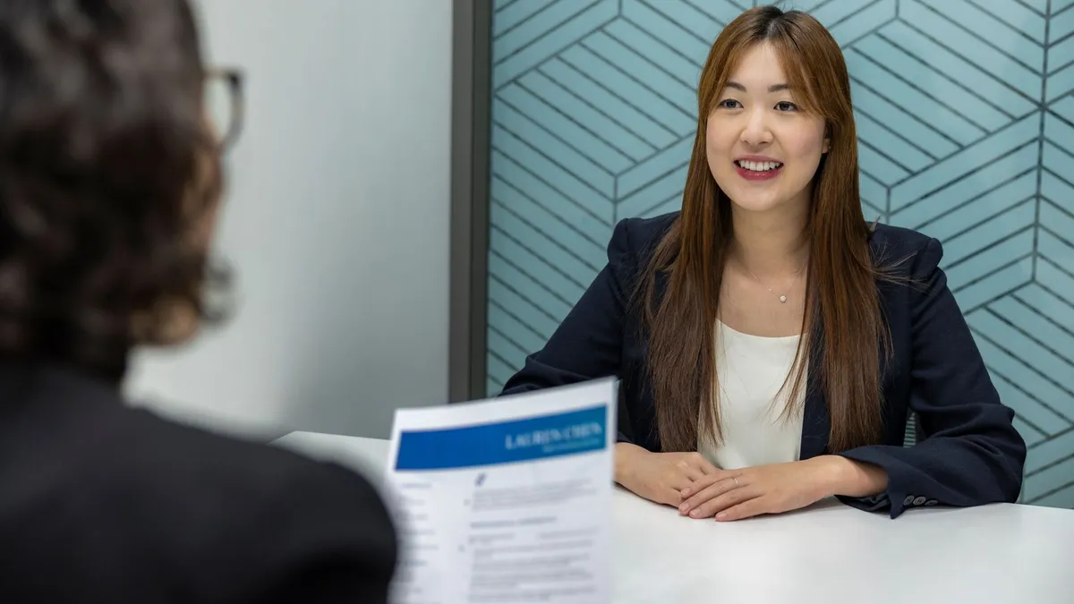 Young woman in a business meeting with an interviewer, showcasing confidence and professionalism.
