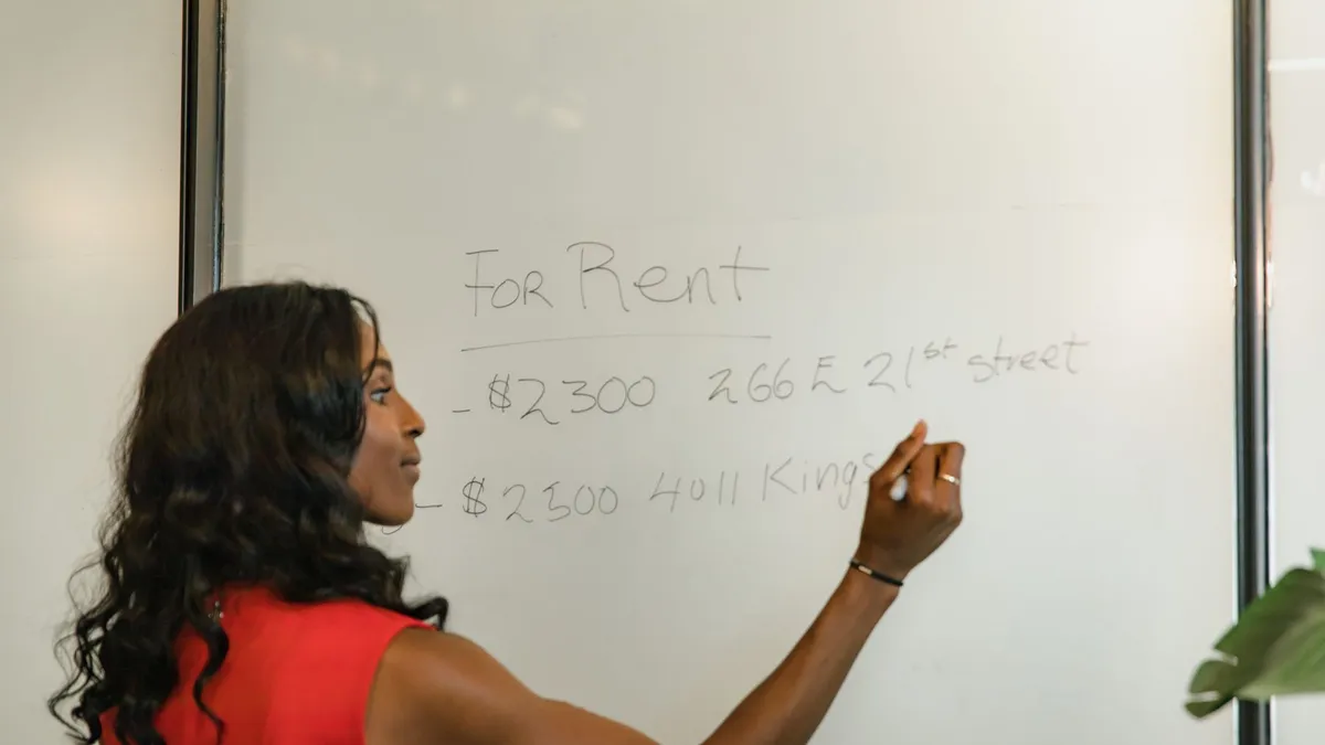 Professional woman writing real estate prices on a whiteboard for rental properties.