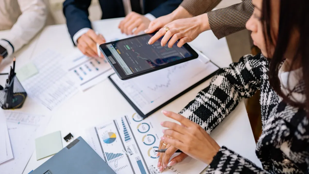 Business professionals reviewing analytics on a tablet during a meeting.