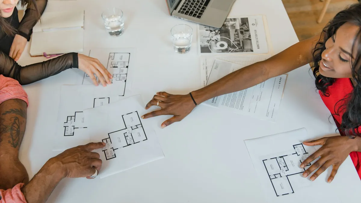 High angle view of diverse business team discussing architectural plans around a table.
