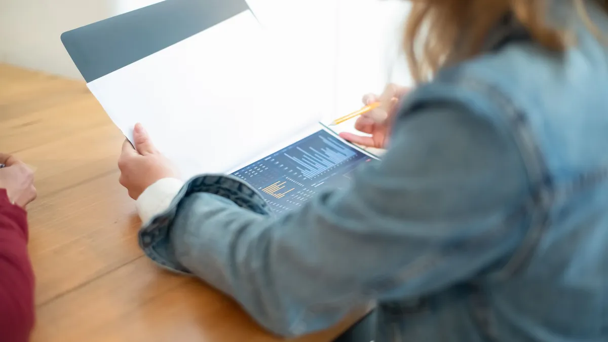 Business meeting discussion with focus on data charts and documents on a desk.