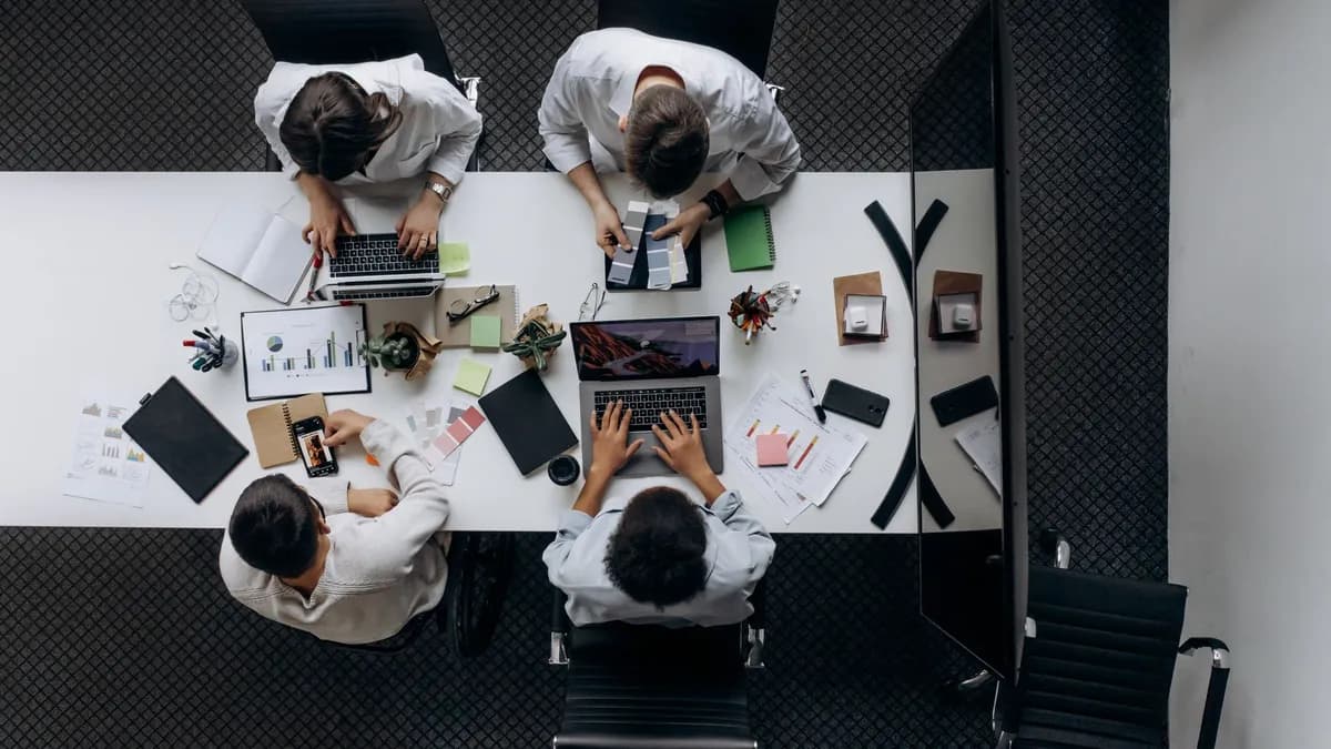 Teamwork in modern office with laptops, charts, and electronic devices from above.