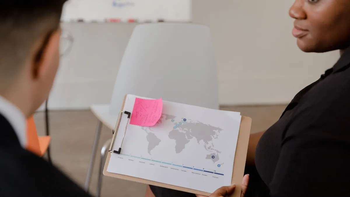 Professional discussion with world map and data visualization on a clipboard.
