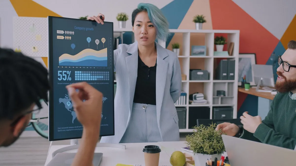 Business team in office reviewing company growth data during a presentation with charts and graphs.