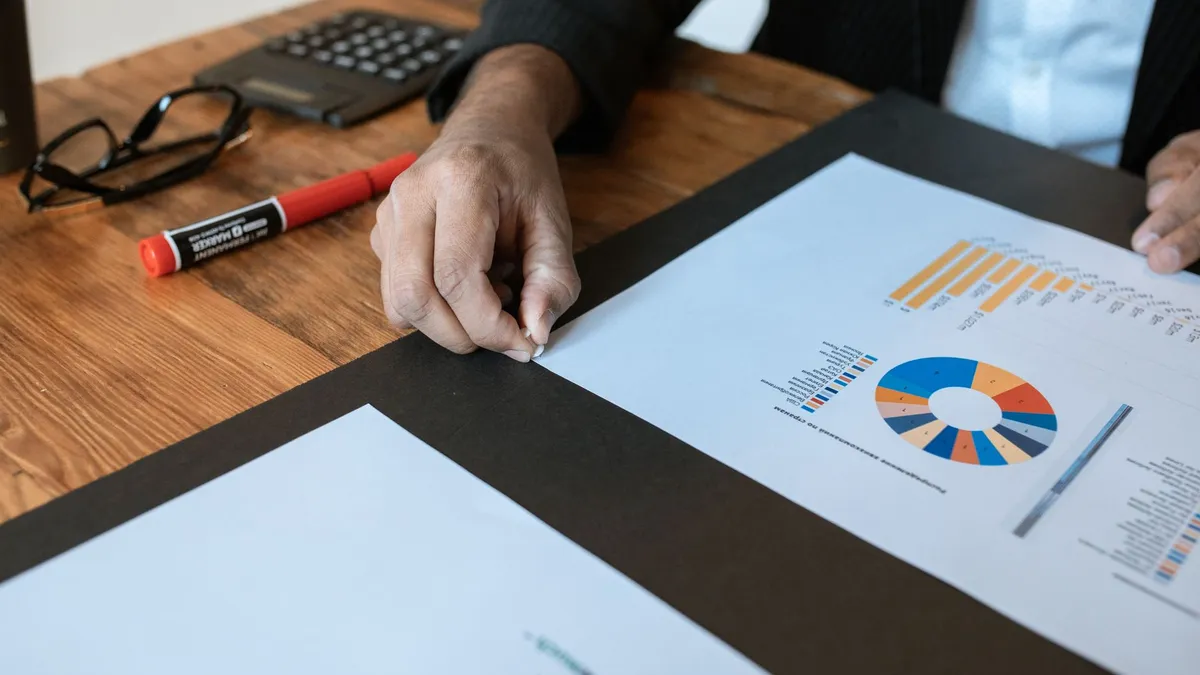 Close-up of a business setting with charts, documents, and a hand pointing.