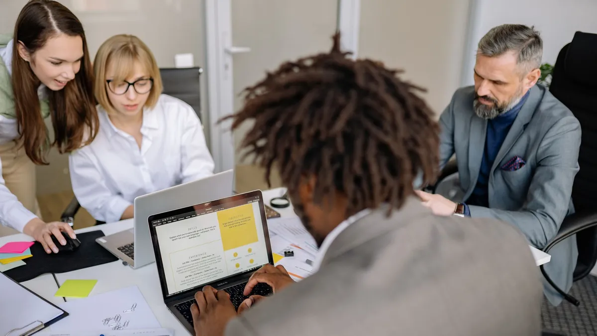 Diverse team working together on a project in an office with laptops and charts.