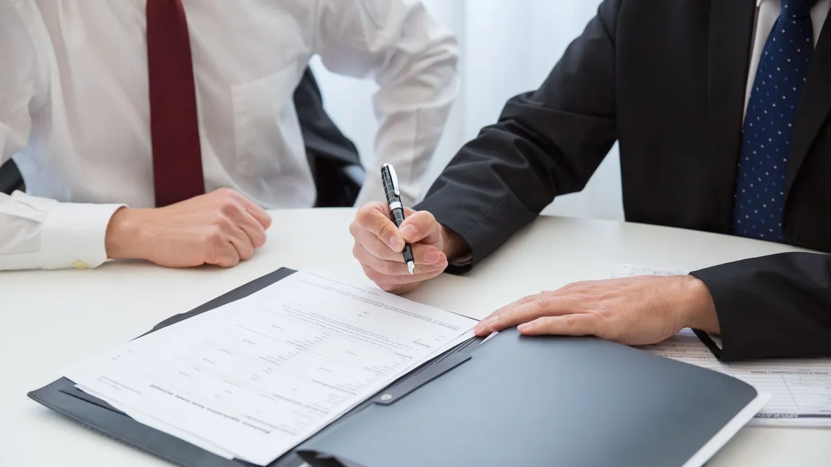 Two professionals signing a contract at a business meeting in an office.