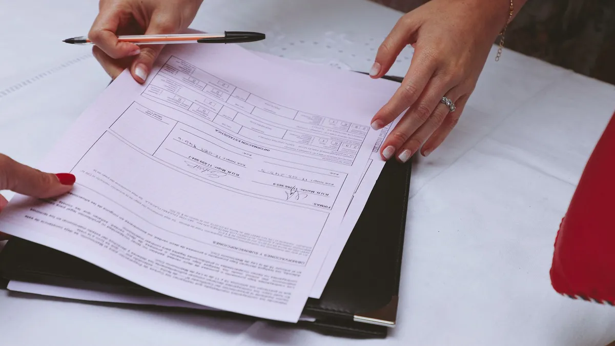 A detailed view of hands working with documents and a pen on a desk, ideal for business themes.