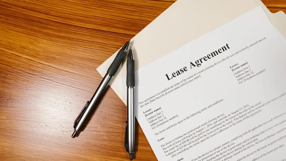High-angle view of a lease agreement and pens on a wooden desk.