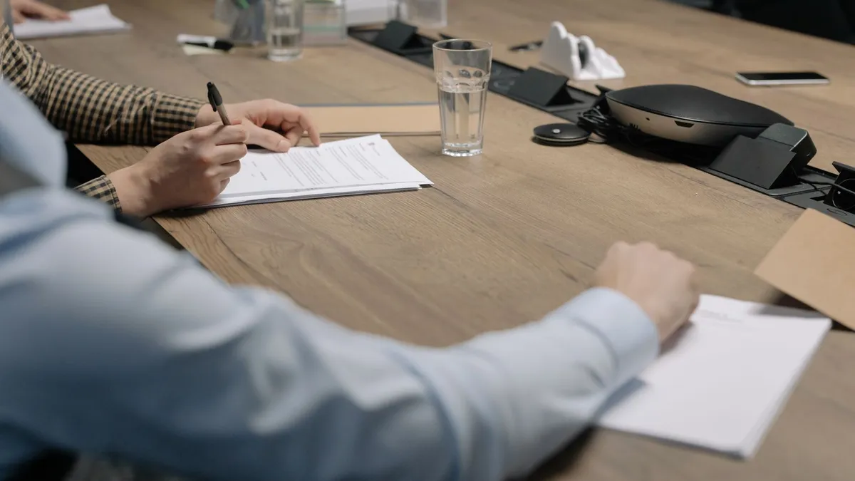 Professional setting of a business meeting with individuals signing documents on a conference table.