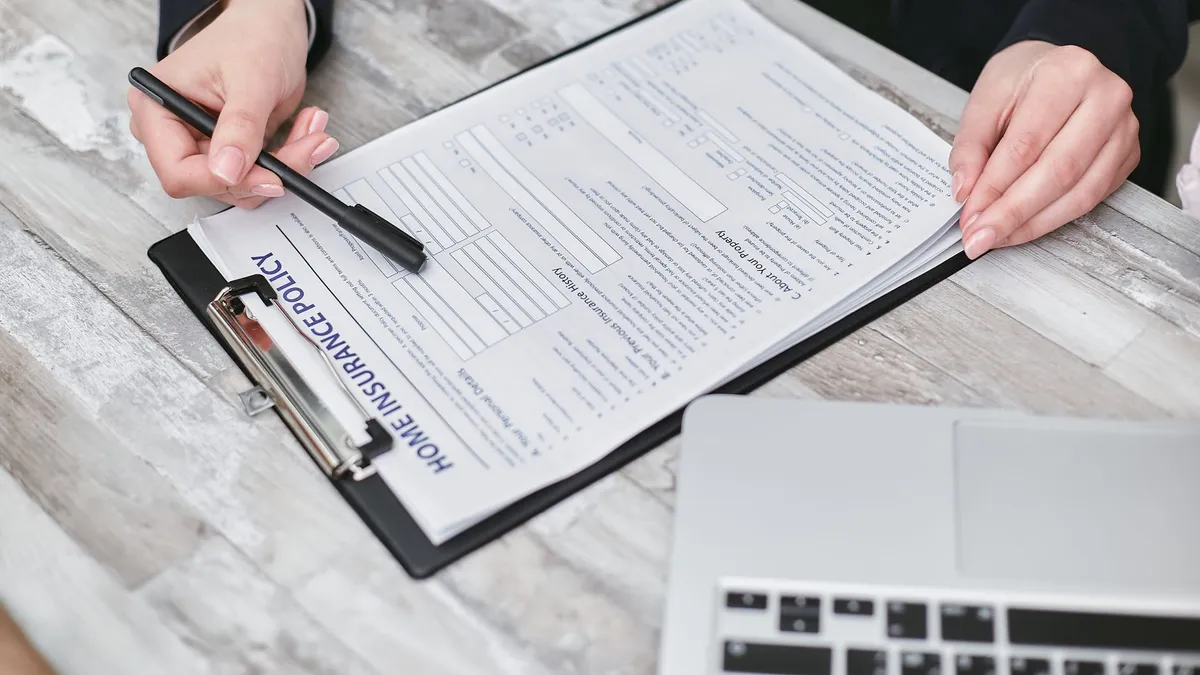 Close-up of hands reviewing a home insurance policy, emphasizing professionalism and finance.
