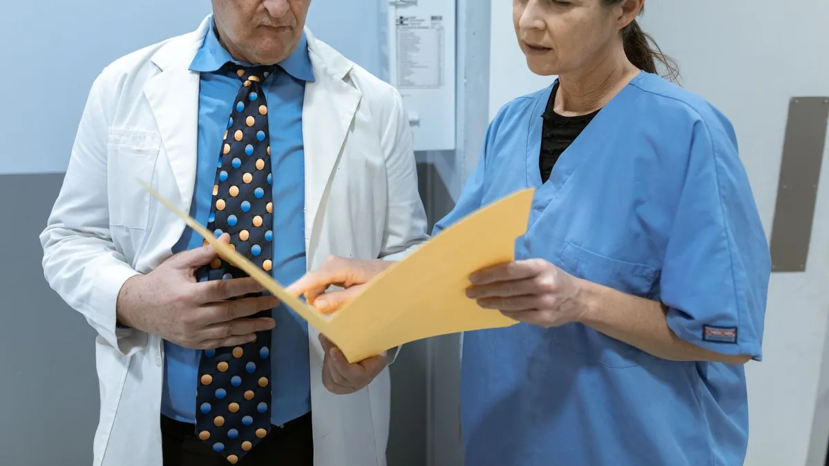 Doctor and nurse examining patient records in a clinical setting.