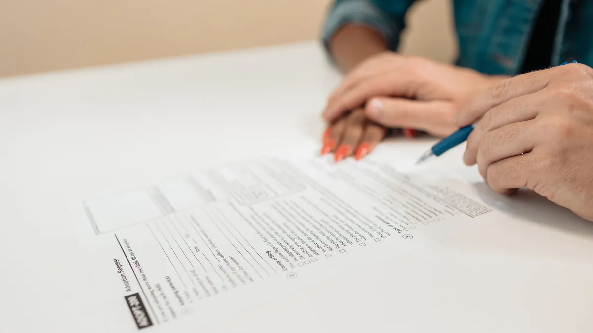 Close-up of hands signing adoption papers in an office environment, symbolizing family and legal process.