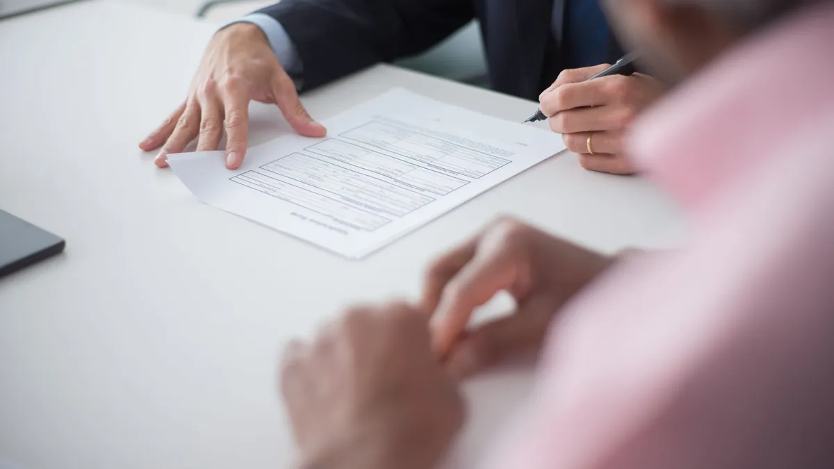 Two professionals engaging in a business meeting, signing documents for a consulting agreement.