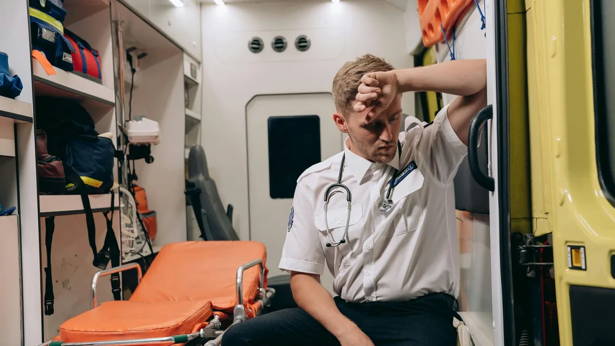 Exhausted paramedic sitting inside an ambulance, reflecting a challenging day.