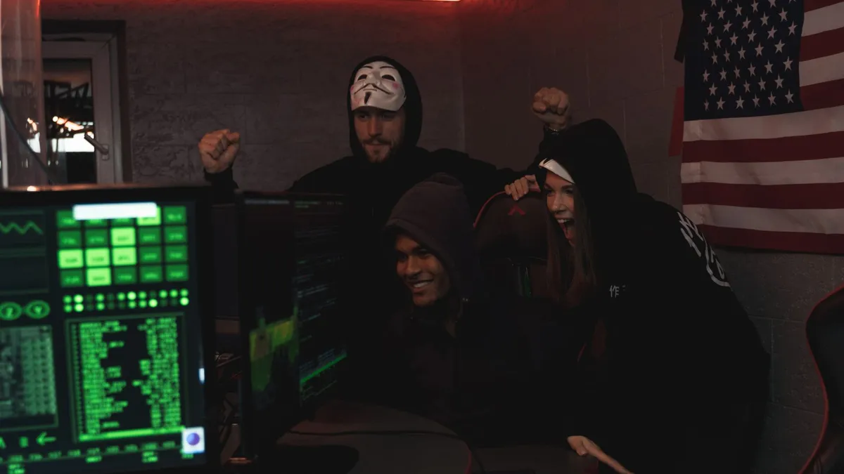 Group of tech enthusiasts in hoodies celebrate a successful cybersecurity operation indoors.