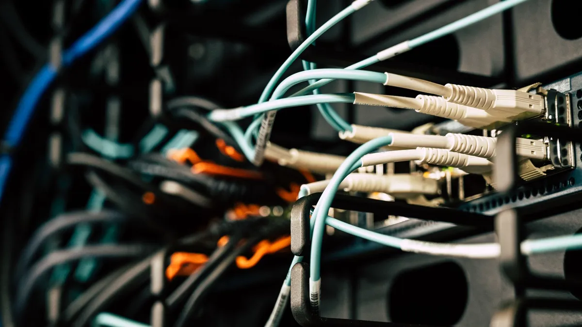 Various tangled wires connected to system near black metal cases in server room