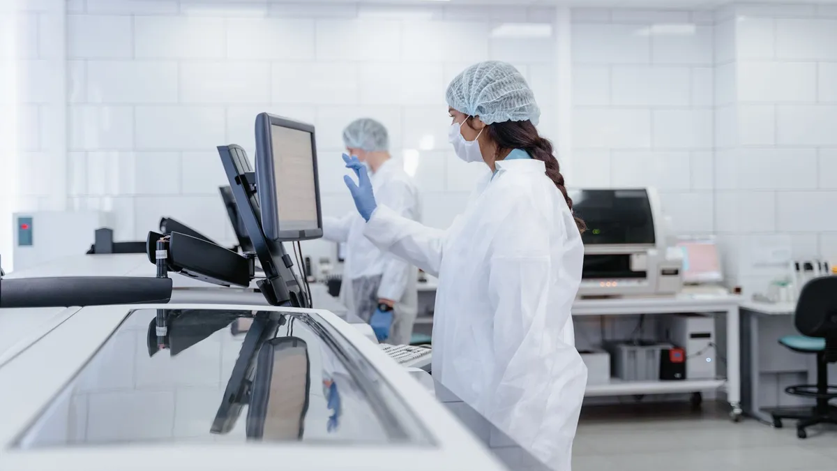 Scientist in protective gear operates equipment in a modern lab.