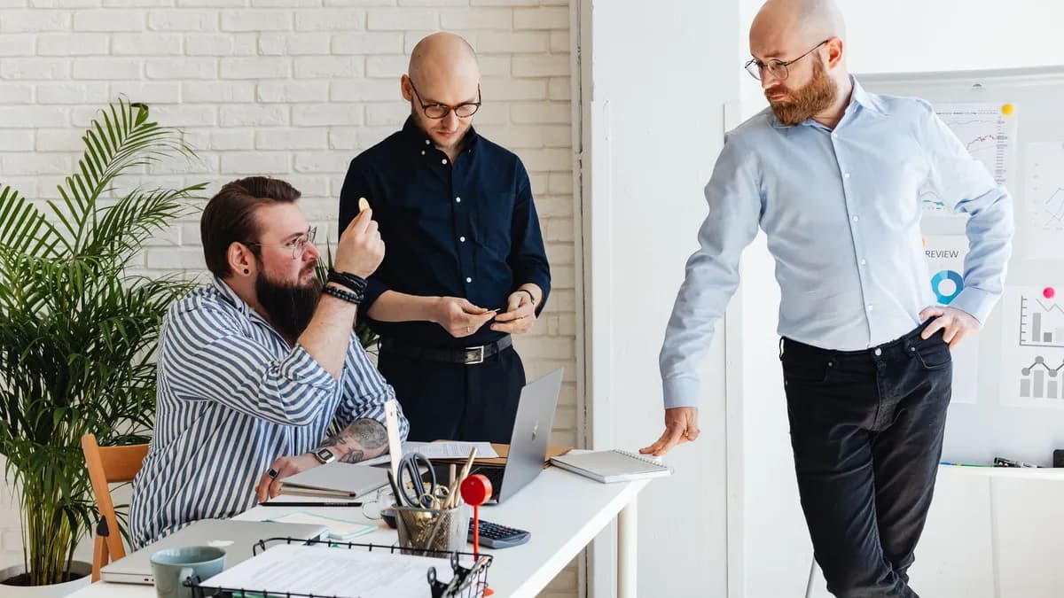 Three men collaborating during a meeting in a bright, modern office setting.